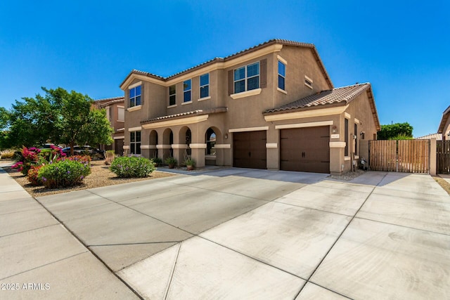 mediterranean / spanish home featuring stucco siding, a gate, fence, a tile roof, and concrete driveway