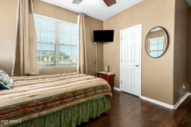 bedroom with dark wood-type flooring, a ceiling fan, and baseboards