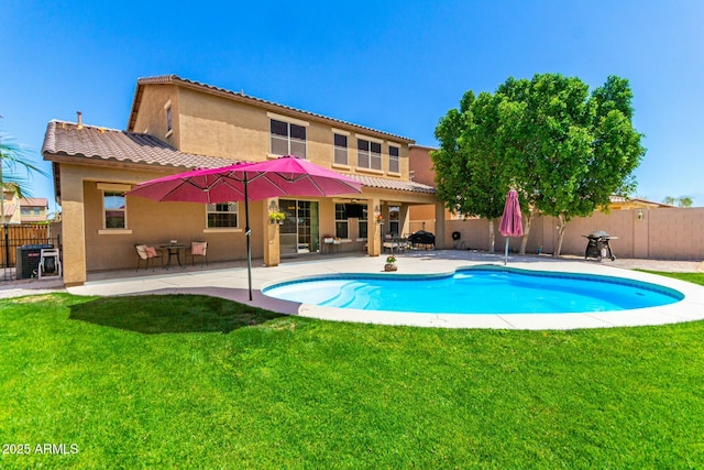 rear view of property featuring stucco siding, fence, a patio area, and a lawn