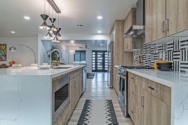kitchen with modern cabinets, ceiling fan, visible vents, wall chimney range hood, and stainless steel appliances