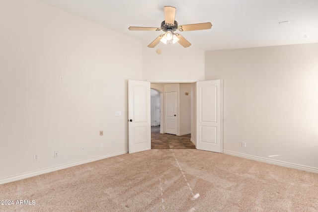 empty room featuring ceiling fan, light colored carpet, and vaulted ceiling