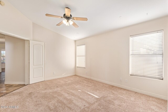 carpeted empty room featuring ceiling fan, a healthy amount of sunlight, and lofted ceiling