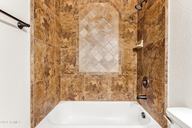 bathroom featuring toilet and tiled shower / bath