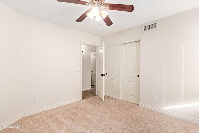 unfurnished bedroom featuring ceiling fan, light colored carpet, and a closet