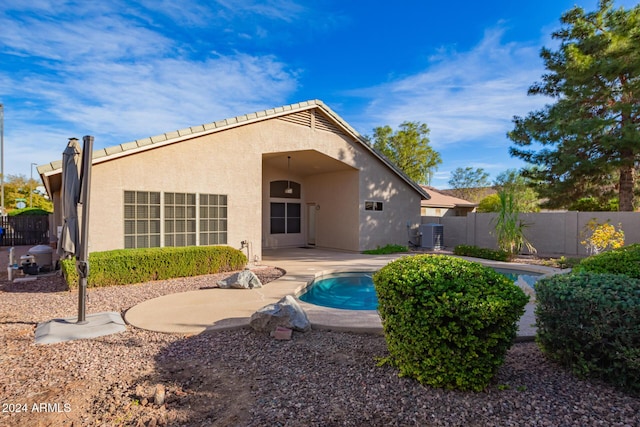 rear view of house featuring a fenced in pool, cooling unit, and a patio area