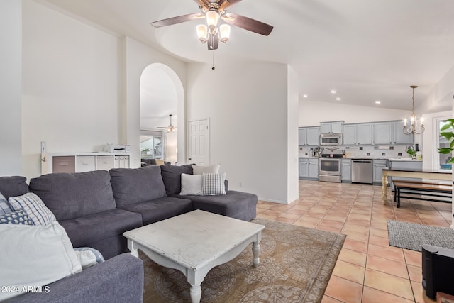 living room with ceiling fan with notable chandelier, high vaulted ceiling, and light tile patterned flooring