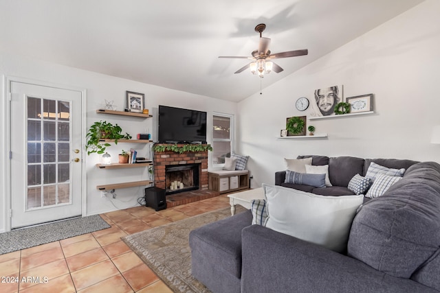 tiled living room featuring a fireplace, vaulted ceiling, and ceiling fan