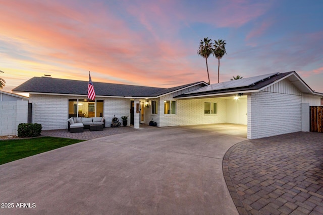 ranch-style home featuring an outdoor hangout area, solar panels, driveway, and fence