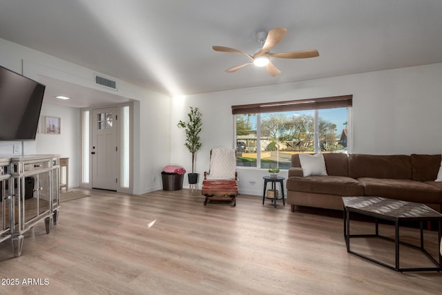 living area with visible vents, light wood-style flooring, baseboards, and a ceiling fan