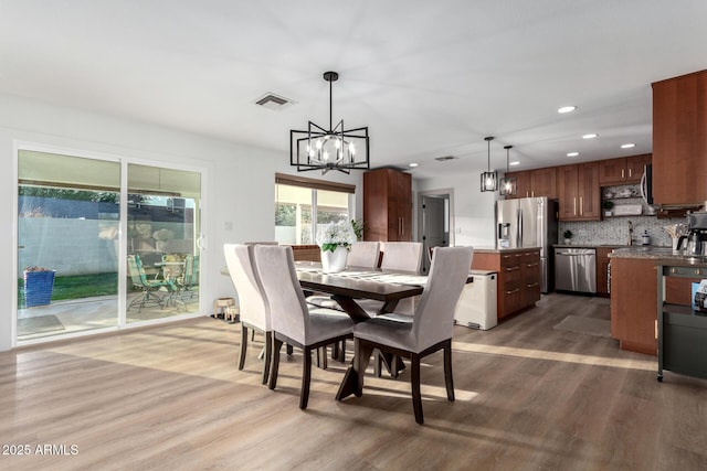 dining space with recessed lighting, visible vents, wood finished floors, and a chandelier