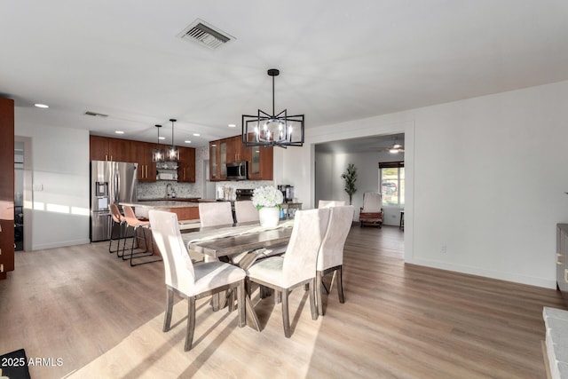 dining space featuring baseboards, visible vents, and light wood finished floors