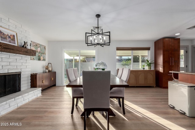 dining area with a chandelier, light wood-style flooring, and a fireplace