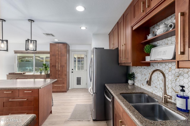 kitchen featuring visible vents, brown cabinets, light wood-style flooring, stone countertops, and a sink