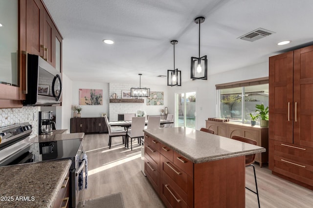 kitchen with visible vents, stainless steel appliances, light wood-style floors, a kitchen bar, and tasteful backsplash