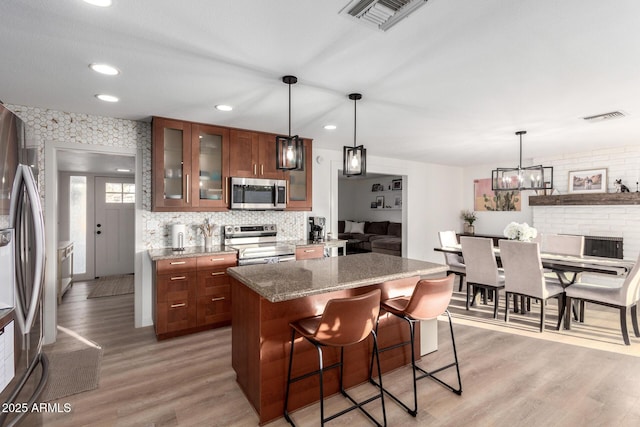 kitchen with visible vents, a breakfast bar area, stainless steel appliances, and light wood-style floors