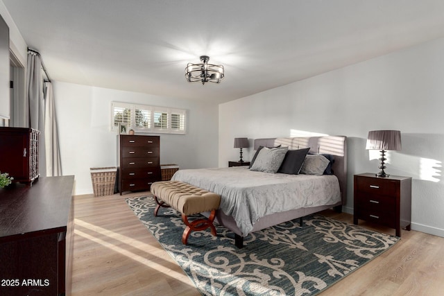 bedroom featuring an inviting chandelier, baseboards, and light wood-type flooring