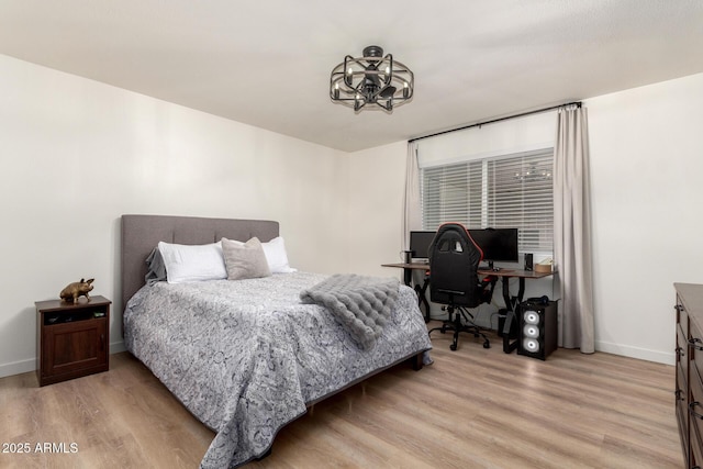 bedroom with a chandelier, baseboards, and light wood-style floors