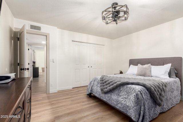 bedroom with a closet, visible vents, baseboards, and light wood-style floors