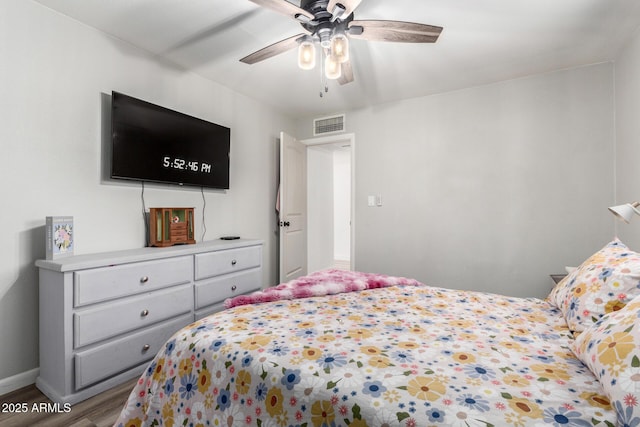 bedroom with visible vents, baseboards, wood finished floors, and a ceiling fan