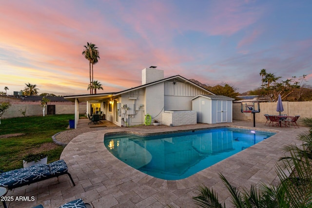 view of pool featuring fence, a shed, outdoor dining area, an outdoor structure, and a patio area