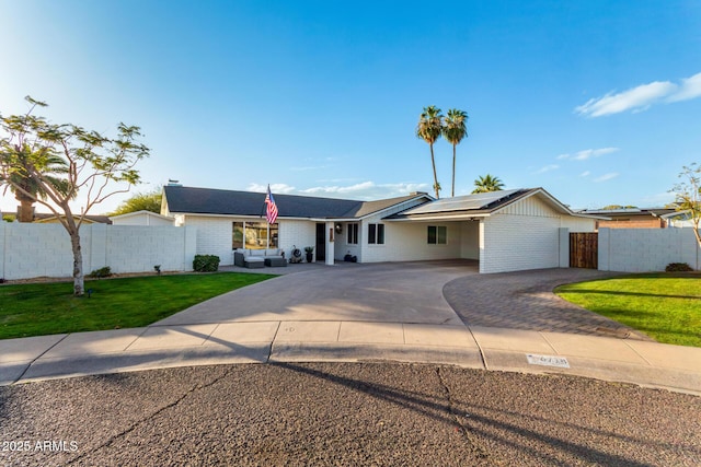 single story home with fence, driveway, solar panels, a front lawn, and brick siding