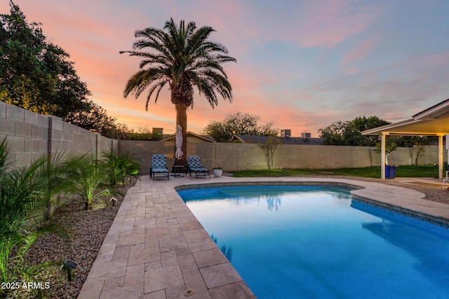 pool at dusk featuring a patio, a fenced backyard, and a fenced in pool