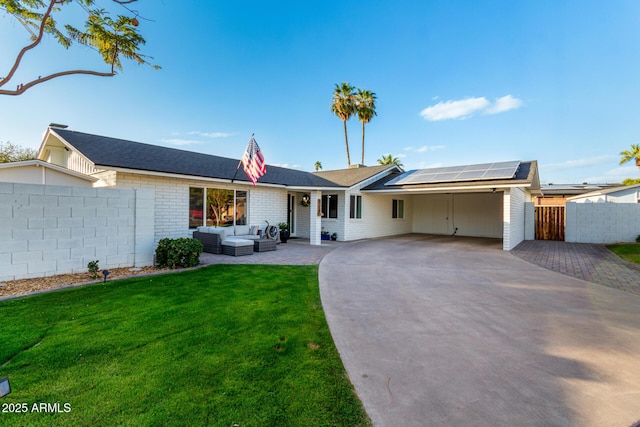 ranch-style home with fence, solar panels, an outdoor living space, concrete driveway, and a front lawn