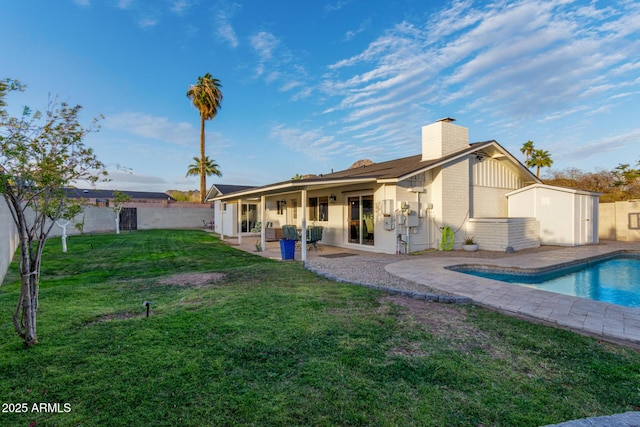 rear view of property with a fenced in pool, fence, a lawn, a chimney, and a patio area