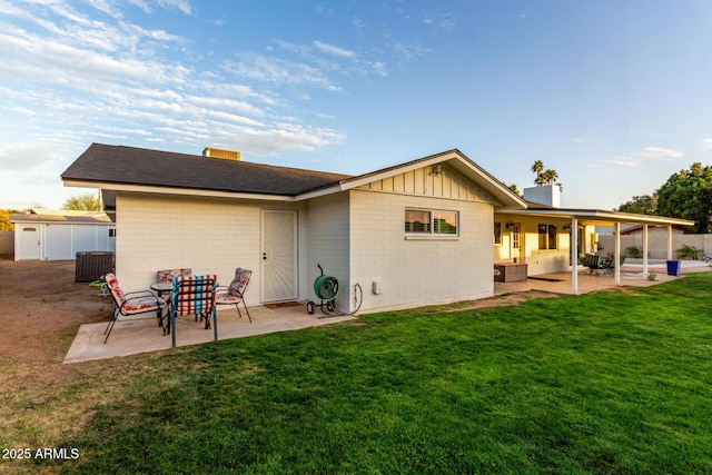 back of house with a patio, a yard, board and batten siding, and a chimney