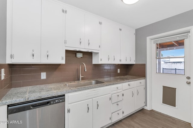 kitchen with sink, light hardwood / wood-style flooring, dishwasher, tasteful backsplash, and white cabinets