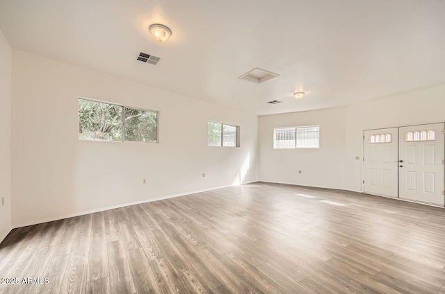 unfurnished room with baseboards, visible vents, and wood finished floors