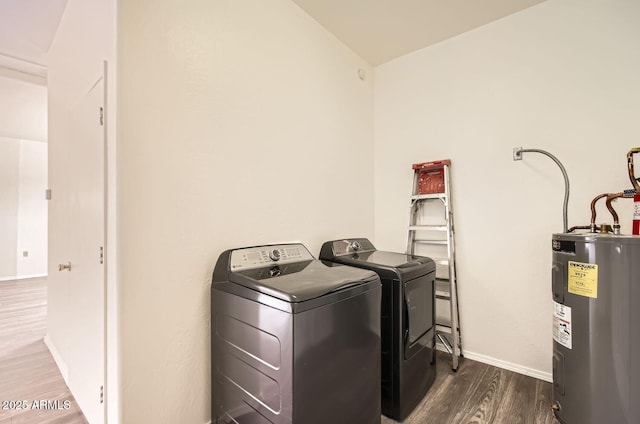 washroom with washing machine and clothes dryer, laundry area, baseboards, dark wood-type flooring, and electric water heater