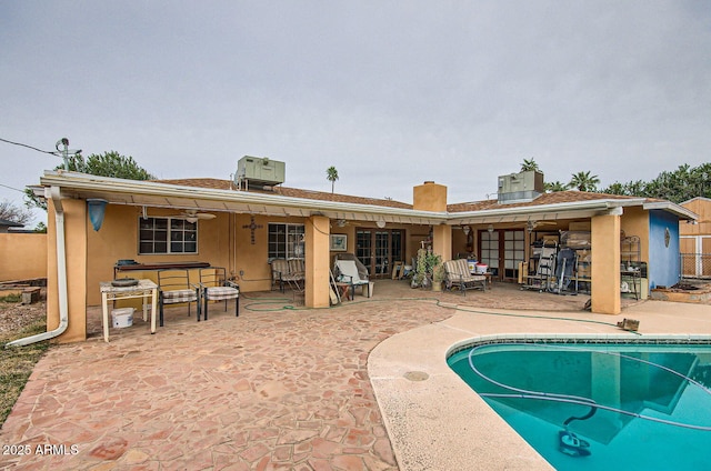 rear view of house featuring stucco siding, a bar, a patio area, and fence