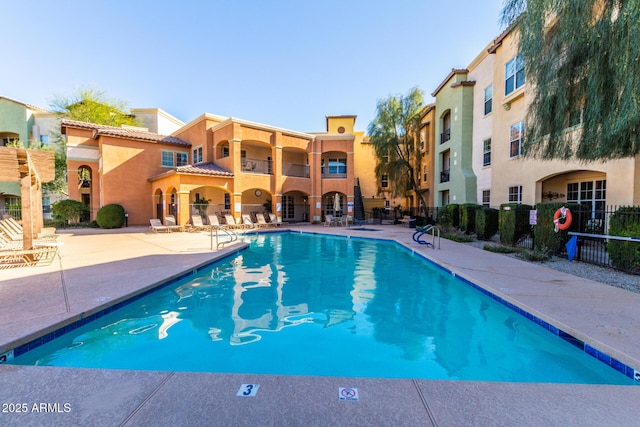 community pool with a patio and fence