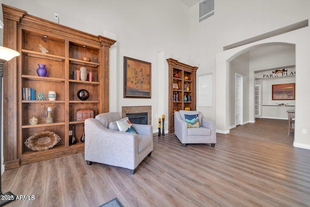 sitting room with arched walkways, visible vents, wood finished floors, and a fireplace
