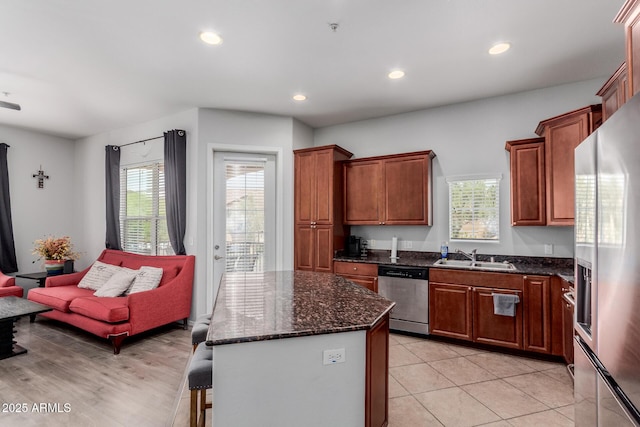 kitchen with a kitchen island, recessed lighting, a sink, dark stone countertops, and stainless steel appliances