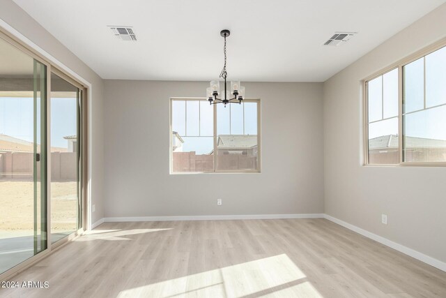 spare room with light hardwood / wood-style floors and a chandelier