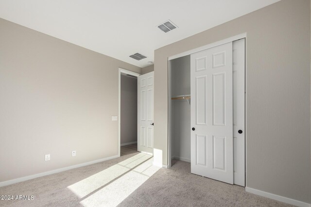 unfurnished bedroom featuring a closet and light carpet