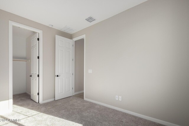 unfurnished bedroom featuring light colored carpet and a closet