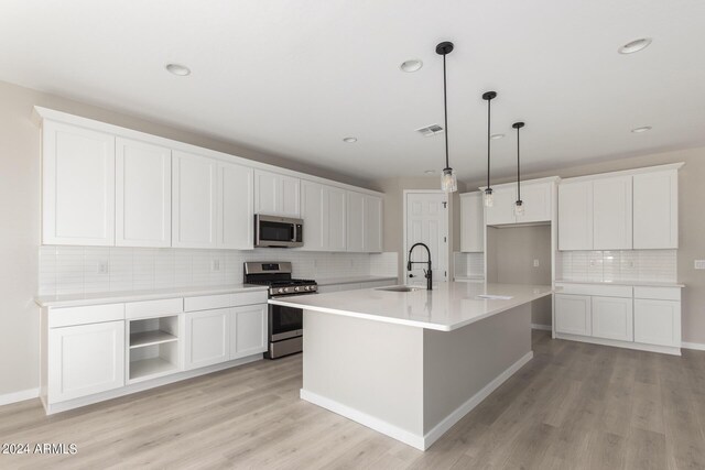 kitchen featuring appliances with stainless steel finishes, a center island with sink, white cabinets, and light hardwood / wood-style floors