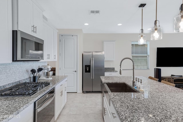 kitchen featuring visible vents, white cabinets, decorative backsplash, light stone countertops, and stainless steel appliances