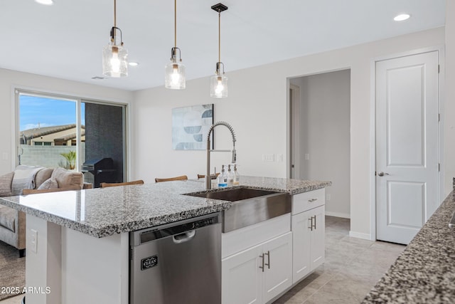 kitchen with white cabinets, light stone counters, stainless steel dishwasher, pendant lighting, and a sink