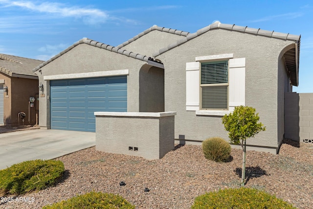 view of front facade with a garage, concrete driveway, a tiled roof, and stucco siding