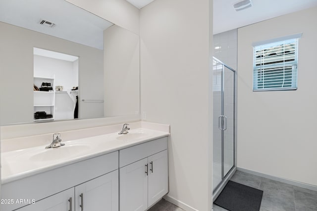 bathroom featuring double vanity, a stall shower, visible vents, and a sink