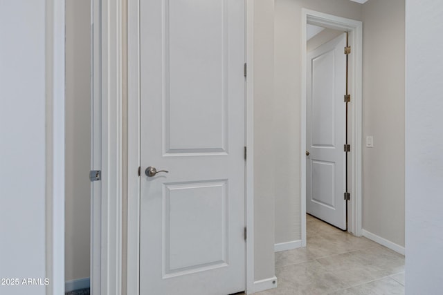 hallway featuring light tile patterned floors and baseboards