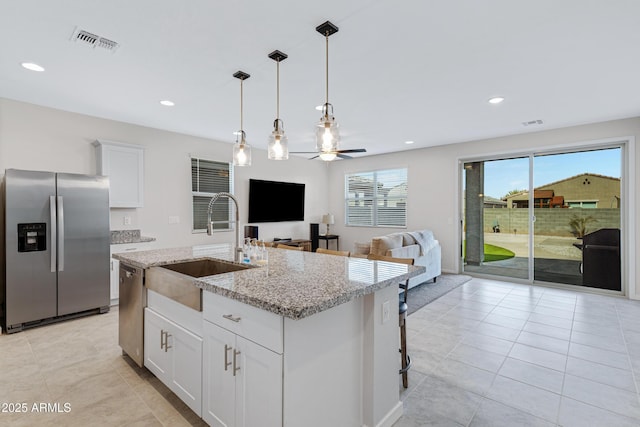 kitchen with visible vents, a kitchen island with sink, stainless steel appliances, white cabinetry, and a sink