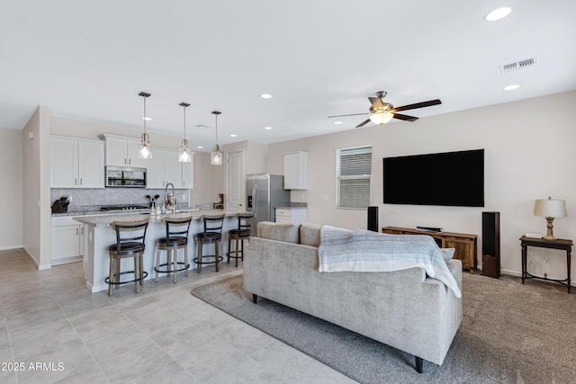 living room featuring ceiling fan, visible vents, baseboards, and recessed lighting