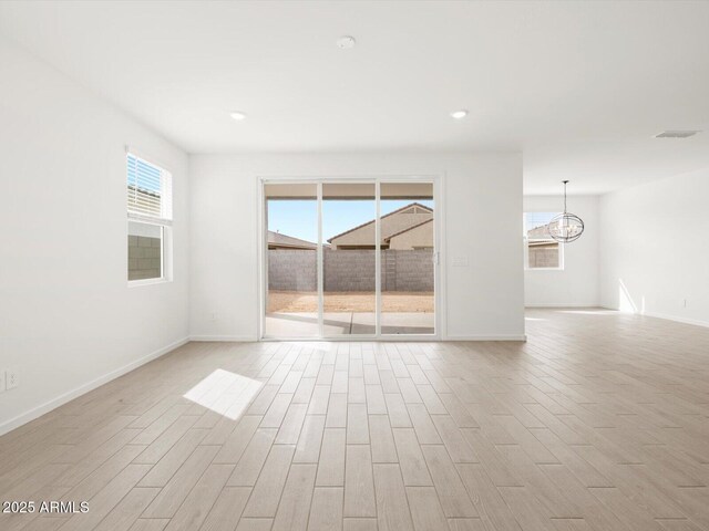 17703 W Southgate Ave, Goodyear, AZ 85338 - spare room featuring a notable chandelier, light wood-style floors, visible vents, and a wealth of natural light