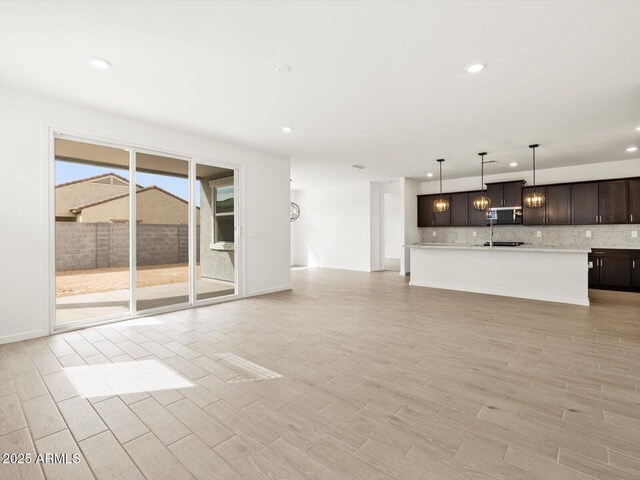 17703 W Southgate Ave, Goodyear, AZ 85338 - unfurnished living room featuring recessed lighting, baseboards, and light wood finished floors