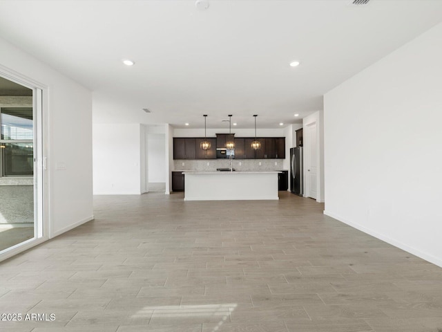 17703 W Southgate Ave, Goodyear, AZ 85338 - unfurnished living room featuring recessed lighting, light wood-type flooring, and baseboards